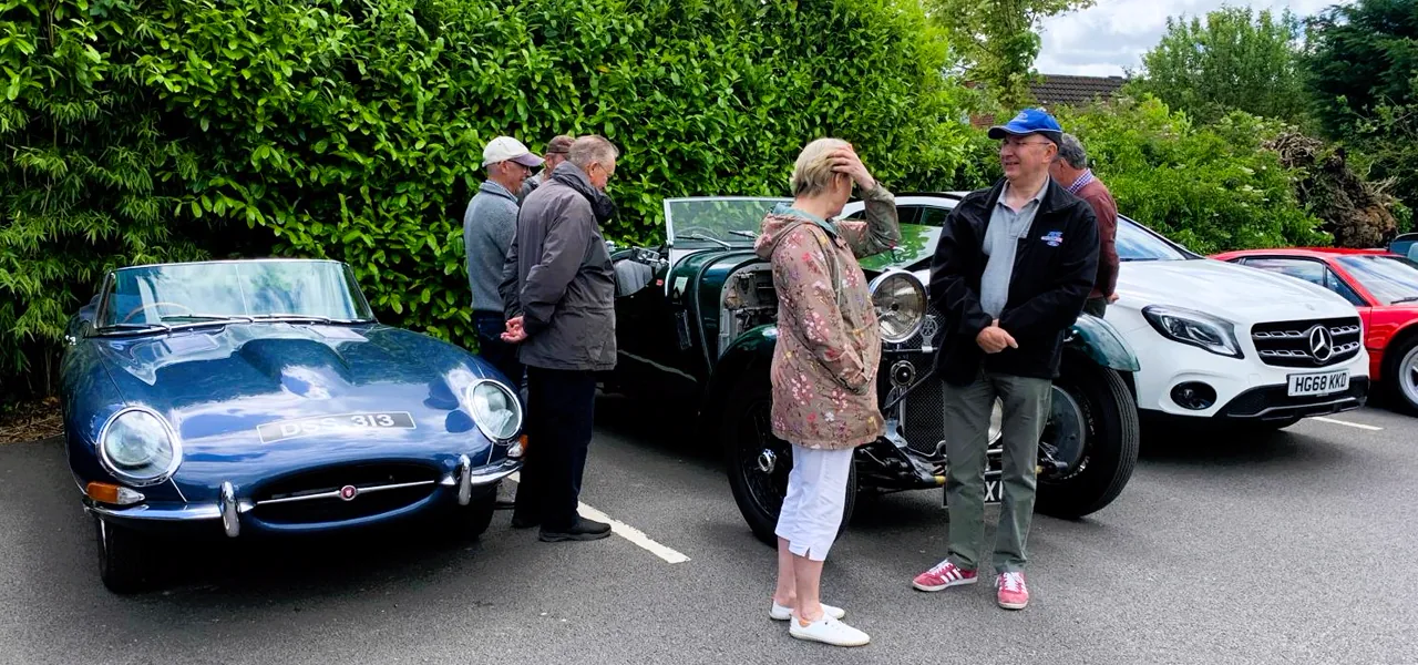 People talking beside a blue Jaguar E-Type